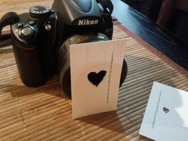 A camera next to business cards with a heart carved out of them